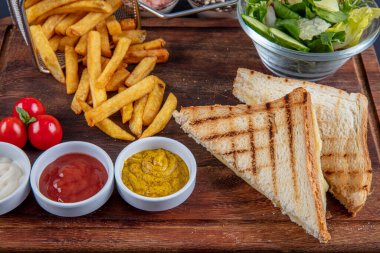 Çedar tostu, tahtanın üzerinde patates kızartmasıyla servis edilir..