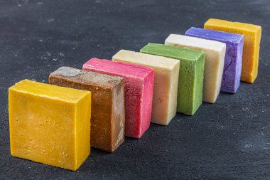 Siyah ahşap arka planda birçok farklı el yapımı sabun kalıbı var. Farklı el yapımı sabunlar, düz yatak, üst manzara. Eko sabun ve kozmetik ürünleri. Doğal sağlıklı ürün..