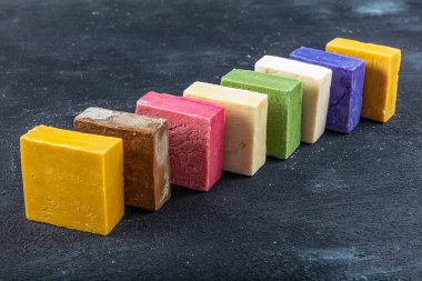 Siyah ahşap arka planda birçok farklı el yapımı sabun kalıbı var. Farklı el yapımı sabunlar, düz yatak, üst manzara. Eko sabun ve kozmetik ürünleri. Doğal sağlıklı ürün..