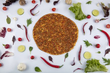 Beyaz arka planda yeşil sebzeler arasında Türk Lahmacunu. Lahmacun Restoranı konsepti.
