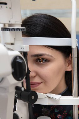 Göz bakımı için yüksek teknoloji konsepti. Göz doktorunun göz kliniğindeki göz doktoru, göz kontrolü için genç bir kadına dürbün lamba kullanıyor.. 