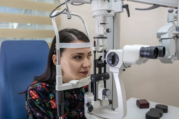 High technology concept health for eyes care - The optician ophthalmology doctor optometrist in the eyes clinic using a binocular slit-lamp to a young woman for an eye control.