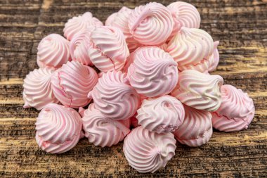 Hazırlık sürecinde Pavlova adında beyaz, kırbaçlanmış, gri ve pembe kremalı pasta. Beyaz, gri ve pembe girdaplar ahşap masada.