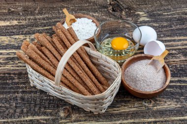 Tahta bir arka planda tam buğday unlu Grissini ekmeği yığını.