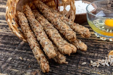 Tahta zemin üzerinde ayçiçeği tohumlu bir buğday yığını Grissini ekmeği..
