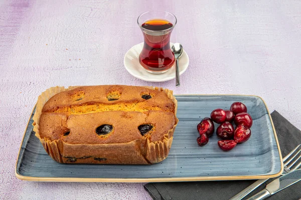 Cherry cake and slices of cherry cake on a baking paper . Cherry sponge cake.