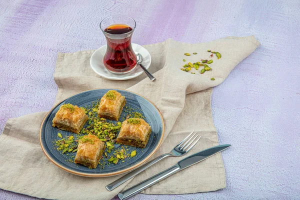Baklava with pistachio, baklava and turkish tea on a serving plate. Patisserie service concept.
