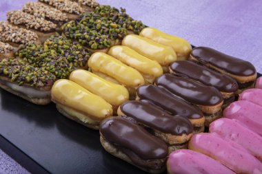 Ekler Pasta / Çikolatalı Donut tabakta. Bir sürü Fransız profiterol (eclair) choux pastası..
