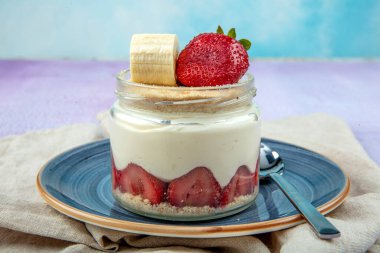 Manolya Tatlısı. Çilek ve Muz Manolyası. Ahşap zemin üzerinde cam bardakta manolya tatlısı..