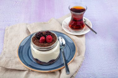 Manolya Tatlısı. Blackberry ve Magnolia. Ahşap zemin üzerinde cam bardakta manolya tatlısı..