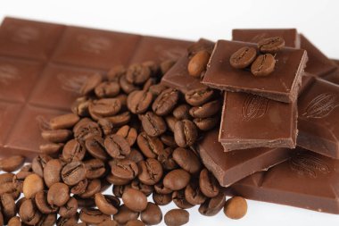 Çikolata-Kahve arka planı: Kırık barın parçalanmış parçaları koyu acı veya sütlü çikolata ve gölgesiz beyaz arka planda izole edilmiş birçok kahve çekirdeği