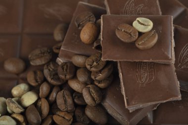 Çikolata-Kahve arka planı: Kırık barın parçalanmış parçaları koyu acı veya sütlü çikolata ve gölgesiz beyaz arka planda izole edilmiş birçok kahve çekirdeği