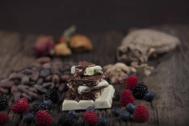 Noel çikolataları. Orman meyveli çikolatalar ve şenlikli arka plan. Fıstıklı fındıklı, beyaz, koyu ve sütlü çikolata karışımı. Macro, seçici odaklanma.