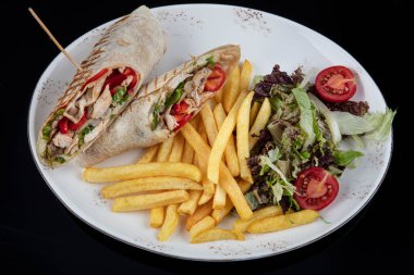 Alternatif taco ya da burrito. İçinde tortilla ile sarılmış geleneksel sandviç dolguları var. Beyaz tabakta servis edilen peynirli tavuklu tortilla..