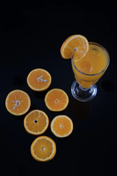 Freshly squeezed orange juice. Fresh orange juice and fresh fruit oranges on a black background.
