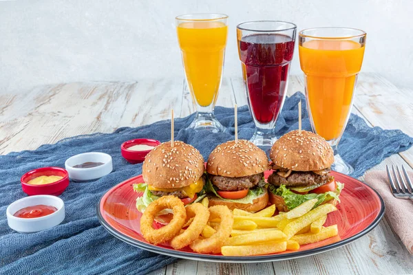 Three mini hamburger. Homemade delicious three mini burgers served with salad, sauce and onion rings and french fries. Homemade mini burger sliders.