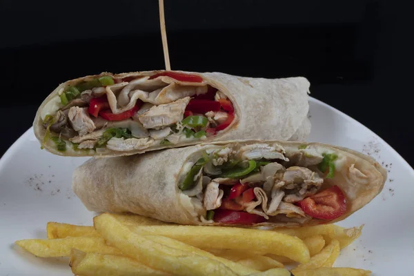 Alternative taco or burrito which includes traditional sandwich fillings wrapped in a tortilla. Cheesy chicken wrap in tortilla served on white plate.