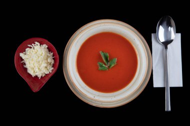 Bir tabak gazpacho - geleneksel İspanyol domates çorbası. Peçete, kaşık, domates, maydanoz, siyah zemin üzerinde beyaz bir kasede domates çorbası..