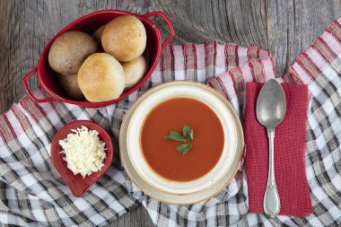 Peçete, kaşık, domates, maydanoz, tahta zemin üzerinde beyaz bir kasede domates çorbası..