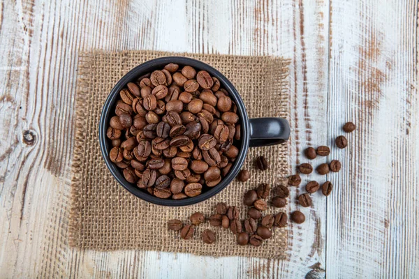 コーヒーカップ コーヒー豆でいっぱい 木製の背景にカップにコーヒー豆 — ストック写真