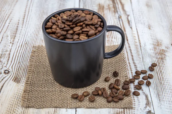コーヒーカップ コーヒー豆でいっぱい 木製の背景にカップにコーヒー豆 — ストック写真