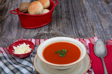 Peçete, kaşık, domates, maydanoz, tahta zemin üzerinde beyaz bir kasede domates çorbası..