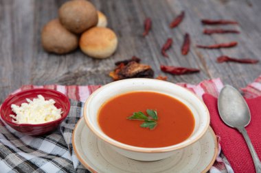 Peçete, kaşık, domates, maydanoz, tahta zemin üzerinde beyaz bir kasede domates çorbası..