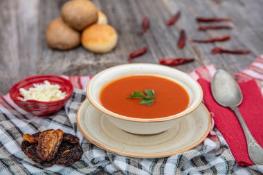 Peçete, kaşık, domates, maydanoz, tahta zemin üzerinde beyaz bir kasede domates çorbası..