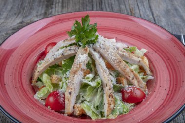 Sağlıklı ızgara tavuklu Sezar salatası ve kızarmış ekmek. Tahta masada taze, sağlıklı sezar salatası pişiyor. Üst görünüm