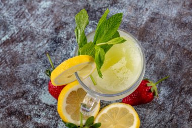Buzlu limonata. Taze limonata, çilekli, naneli, sade bir masanın üstünde..