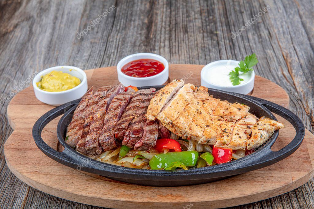 Combo Fajita; bistec mexicano y fajitas de pollo en sartén de hierro con pimientos y cebolla