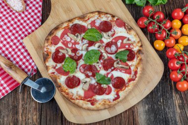 Mozzarella peynirli Pepperoni Pizza, sucuk, domates, biber, baharat ve taze fesleğen. Tahta masada İtalyan pizzası. kopyalama alanı ile.