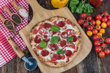 Mozzarella peynirli Pepperoni Pizza, sucuk, domates, biber, baharat ve taze fesleğen. Tahta masada İtalyan pizzası. kopyalama alanı ile.