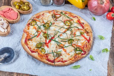 İtalyan Lezzetli Sıcak Karışık Fırında Tavuk Pizzası Eritilmiş Peynir, acılı biber, dilimlenmiş beyaz soğan, mantar, ahşap masa sade arka planda.