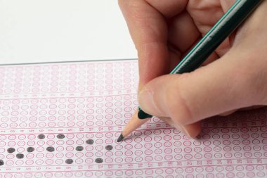 Sınavlara giren öğrencilerin elleri, optik test formunda kalem tutarak sınav kağıtları hazırlıyor ve sınıfta sınav kağıtları hazırlıyor. Eğitim Değerlendirme Kavramı. Yumuşak odak 