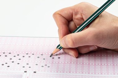 Sınavlara giren öğrencilerin elleri, optik test formunda kalem tutarak sınav kağıtları hazırlıyor ve sınıfta sınav kağıtları hazırlıyor. Eğitim Değerlendirme Kavramı. Yumuşak odak 