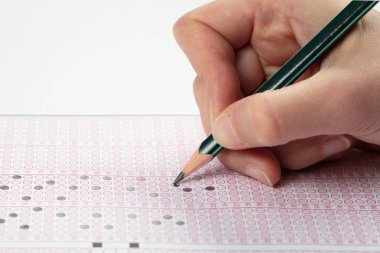 Sınavlara giren öğrencilerin elleri, optik test formunda kalem tutarak sınav kağıtları hazırlıyor ve sınıfta sınav kağıtları hazırlıyor. Eğitim Değerlendirme Kavramı. Yumuşak odak 