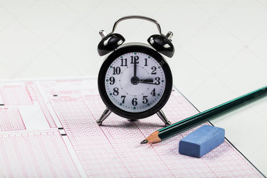 School Students hands taking exams, writing examination holding pencil on optical form of standardized test with answers sheet doing final exam in classroom. Education assessment Concept. Soft focus 