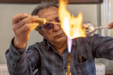 Bir atölyedeki değerli kristalin el yapımı şarap kadehinde ateşle çalışan makro cam üfleyiciyi kapat. El yapımı, yüksek kalite, zanaatkar, İstanbul, Türkiye yapımı, cam üfleme. 