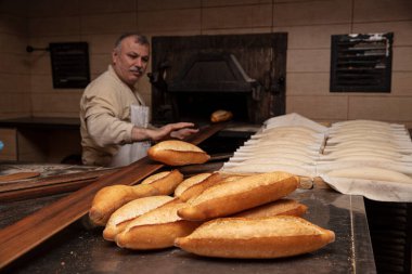 Fırın, ekmek yapma. Baker fırından taze ekmek alıyor. Türk ekmeği üretim süreci. 