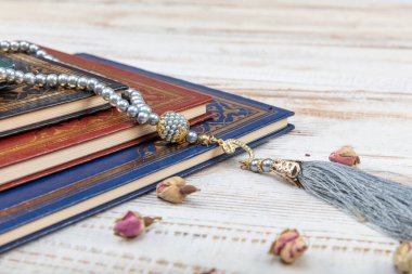 Kutsal Kur 'an' ın Arapça el yazısı ve ahşap masa üzerindeki tespih anlamına gelir. Seçici odak ve kırpma parçası.