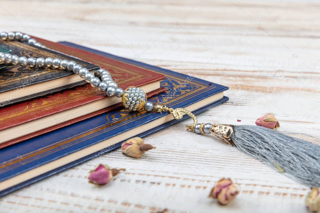 Holy Quran with arabic calligraphy meaning of Al Quran and tasbih or rosary beads over on wooden table. Selective focus and crop fragment.