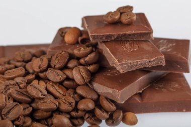 Çikolata-Kahve arka planı: Kırık barın parçalanmış parçaları koyu acı veya sütlü çikolata ve gölgesiz beyaz arka planda izole edilmiş birçok kahve çekirdeği