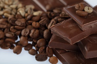 Çikolata-Kahve arka planı: Kırık barın parçalanmış parçaları koyu acı veya sütlü çikolata ve gölgesiz beyaz arka planda izole edilmiş birçok kahve çekirdeği