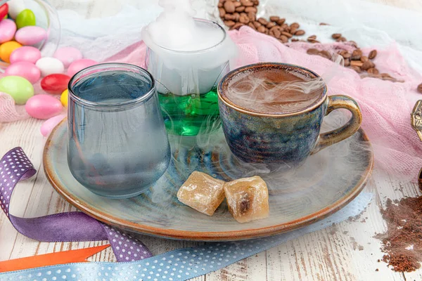 Traditional turkish coffee in porcelain cup set,a glass of water and turkish delight, colorful almond candies on surface with coffee beans. A feast (feast)classic, Ramadan feast catering presentation.