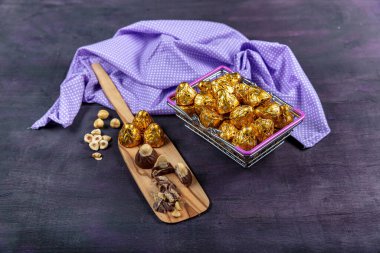 Fındıklı çikolata, fındıklı çikolata, mor ahşap arka planda altın folyoya sarılır. Kurban Bayramı (Ramazan Bayramı) kavramı.