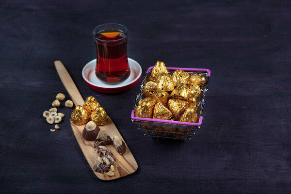 Hazelnut chocolate; Hazelnut Chocolate is wrapped in golden foil, on purple wooden background. Eid al-Fitr (Feast of Ramadan) concept.