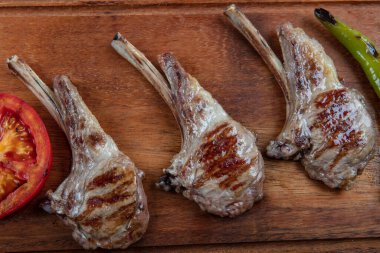 Tahta tabakta et: ahşap üzerinde pirzola, domates, biber ve ahşap masada kuru baharat.