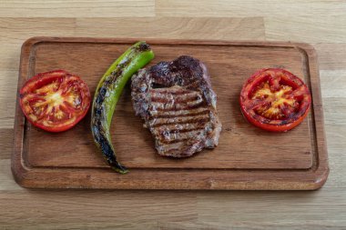 Izgara sebzeli biftek ve ahşap arka planda baharat..
