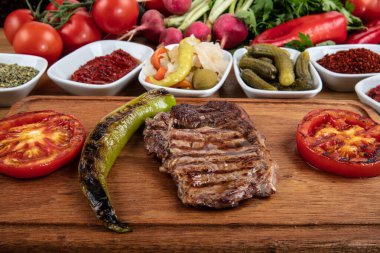 Izgara sebzeli biftek ve ahşap arka planda baharat..